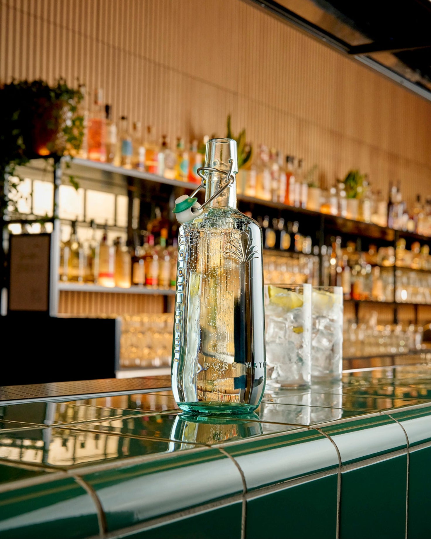 Clear glass bottle on a bar counter with a well-stocked bar in the background